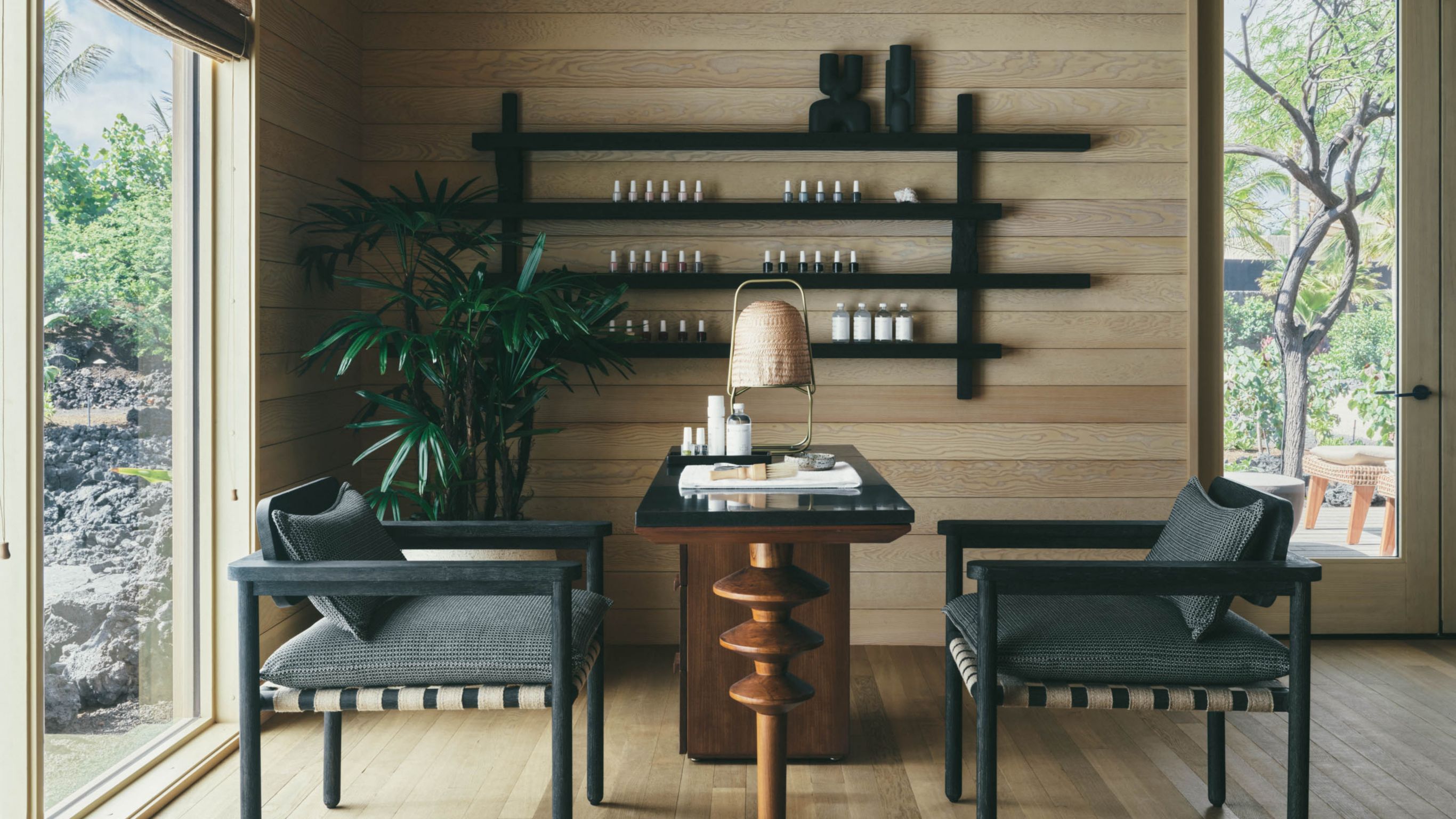 A nail salon with two chairs, a table, and  shelves with nail polishes.